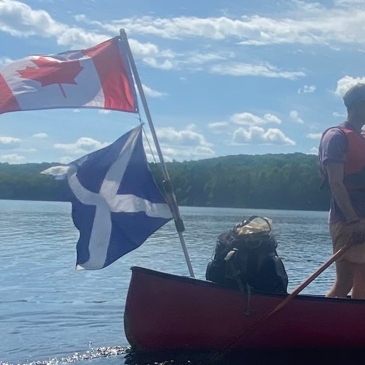 Paddling a canoe flying the Canadian and Scottish flags